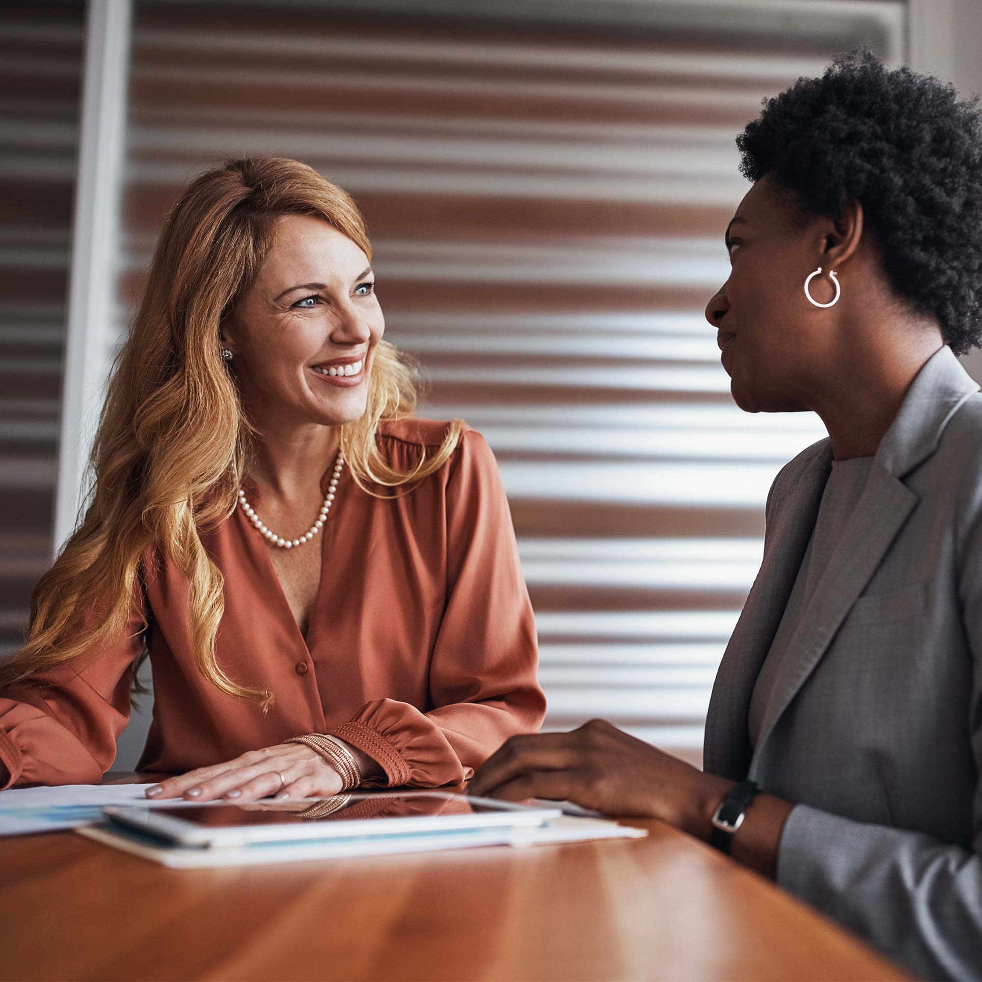 Two women conversing as they sit at a table.